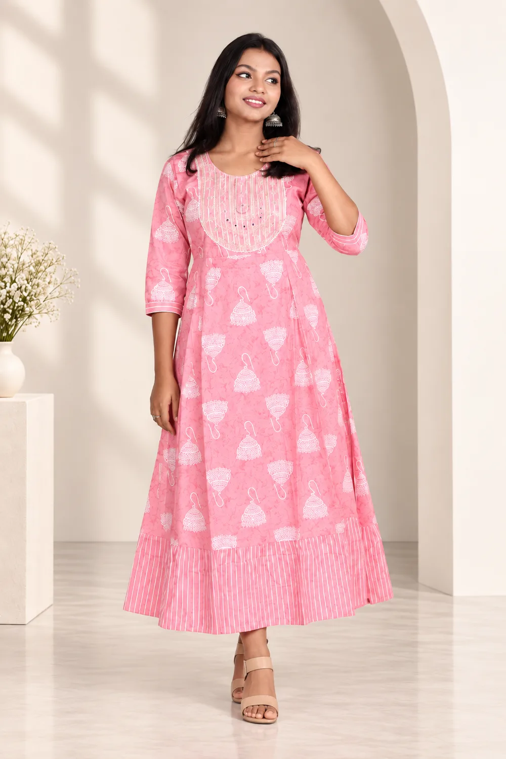 Model in a pink printed A-line kurta set in a sunlit arched courtyard